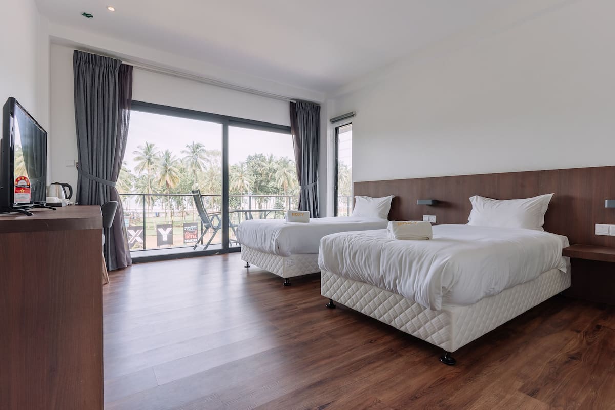A hotel room with two beds, a desk, and a television.