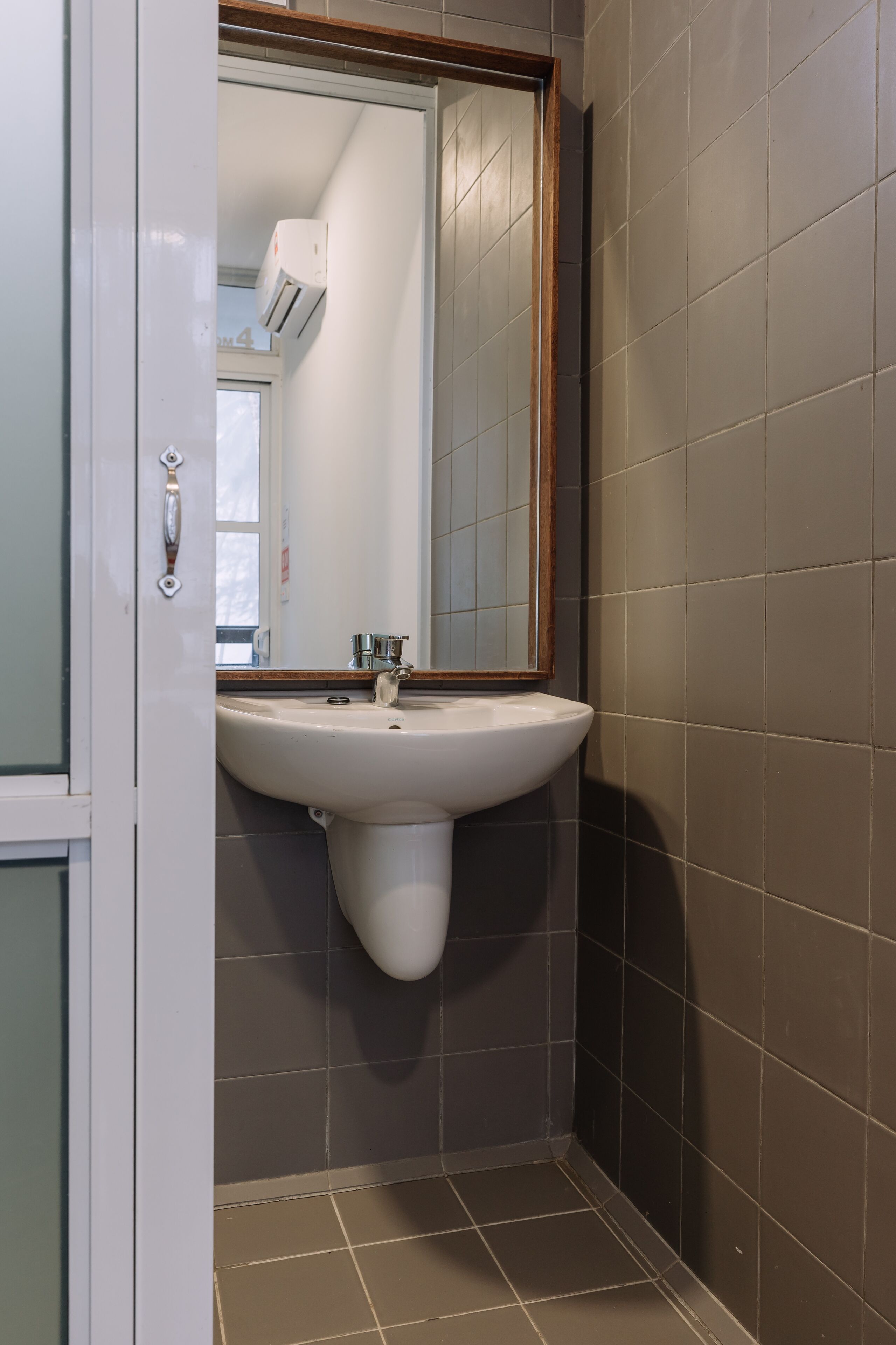 Une salle de bain avec un lavabo blanc, un miroir et une fenêtre.