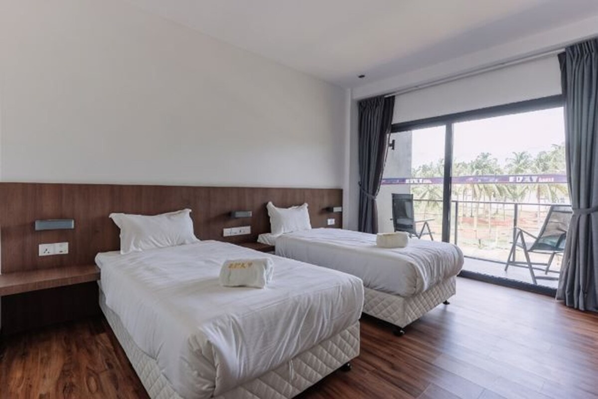 A hotel room with two beds, a balcony with a view, and a wooden floor.
