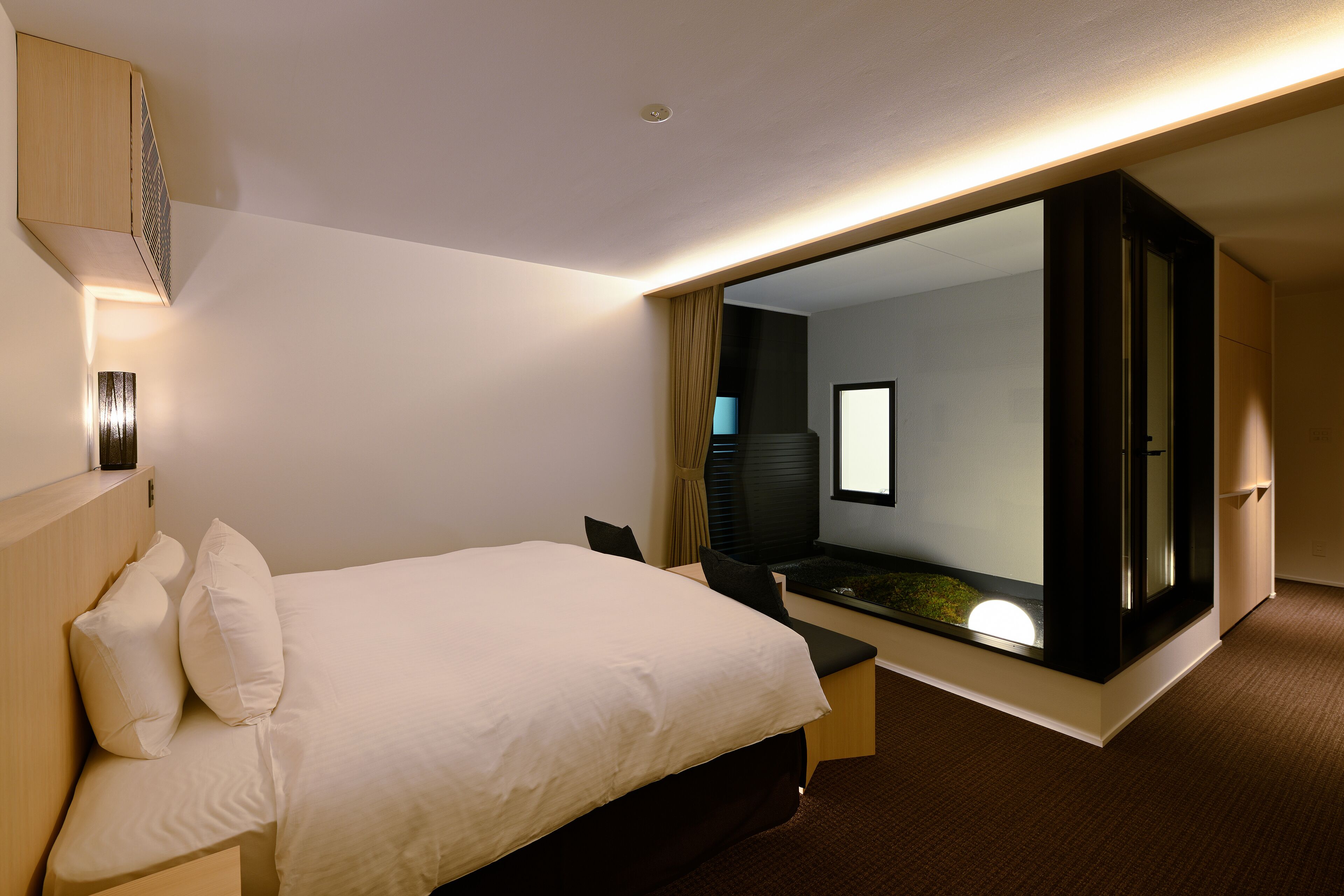 A modern hotel room with a large bed, a desk, and a walk-in closet.
