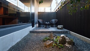 An outdoor seating area with two chairs and a table, surrounded by gravel and rocks. - HOTEL KYOTOLOGY (Kyoto)
