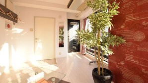 A modern hotel lobby with a glass coffee table, a potted plant, and a red wall with decorative script. - Balcone Uchikyuhoji (Osaka)