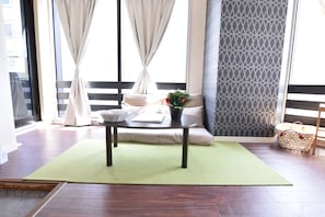 A room with a sofa, a table with a plant, a basket, and a patterned wall.