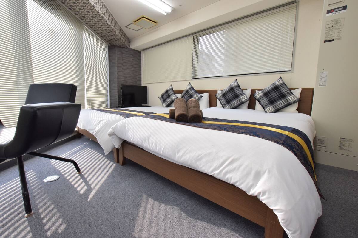Quarto de hotel com uma cama, uma cadeira e uma televisão.