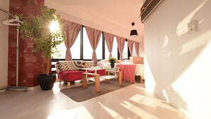 A modern living room with a red sofa, a glass coffee table, and a large window with curtains. - Balcone Uchikyuhoji (Osaka)