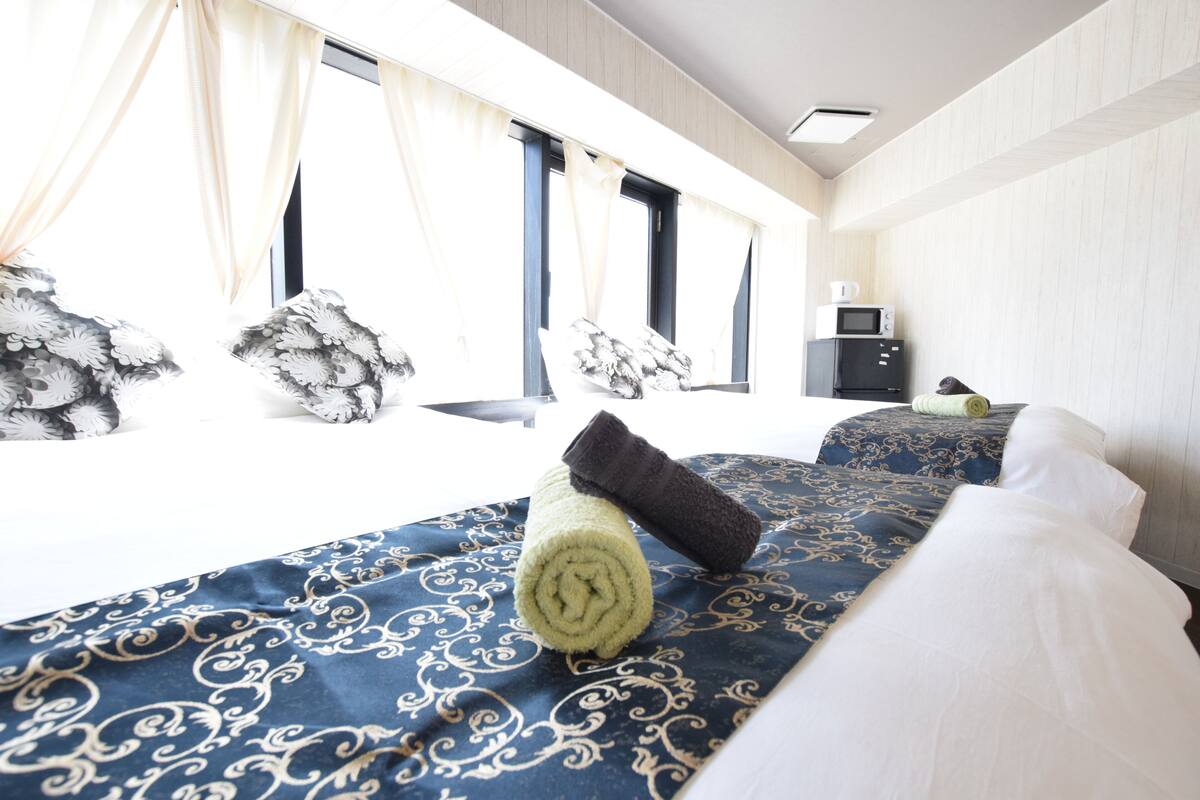 Quarto de hotel com uma cama grande, micro-ondas e janela com cortinas.