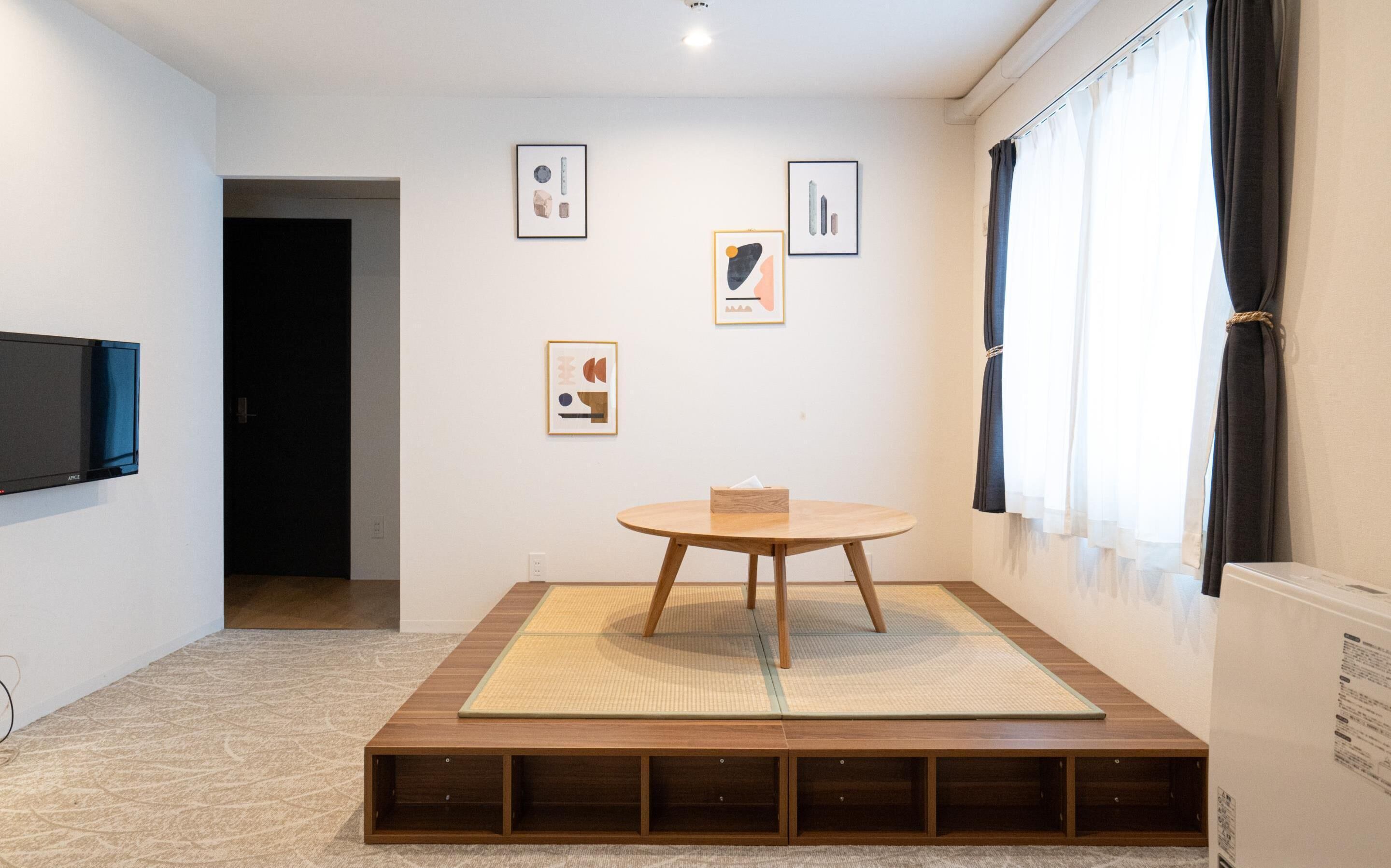A minimalist room with a tatami mat, a wooden table, and framed artwork on the walls.