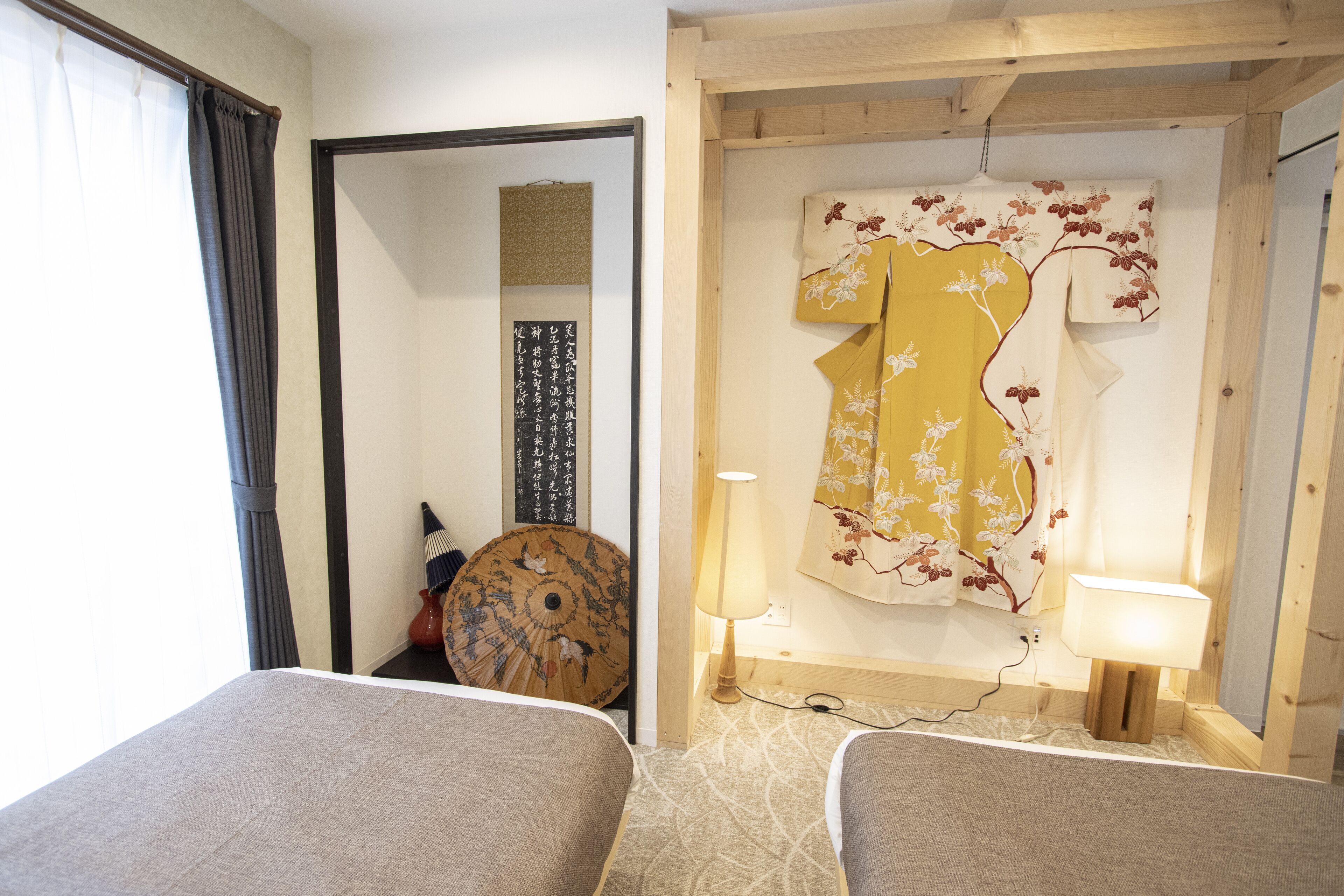 A hotel room with two beds, a traditional Japanese shoji screen, a hanging kimono, and a lamp.