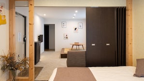 A modern hotel room with a wooden ceiling, a bed with a white and brown bedspread, a small round table, and a dark wooden wardrobe. - UCHI Susukino 5.7 (Sapporo)