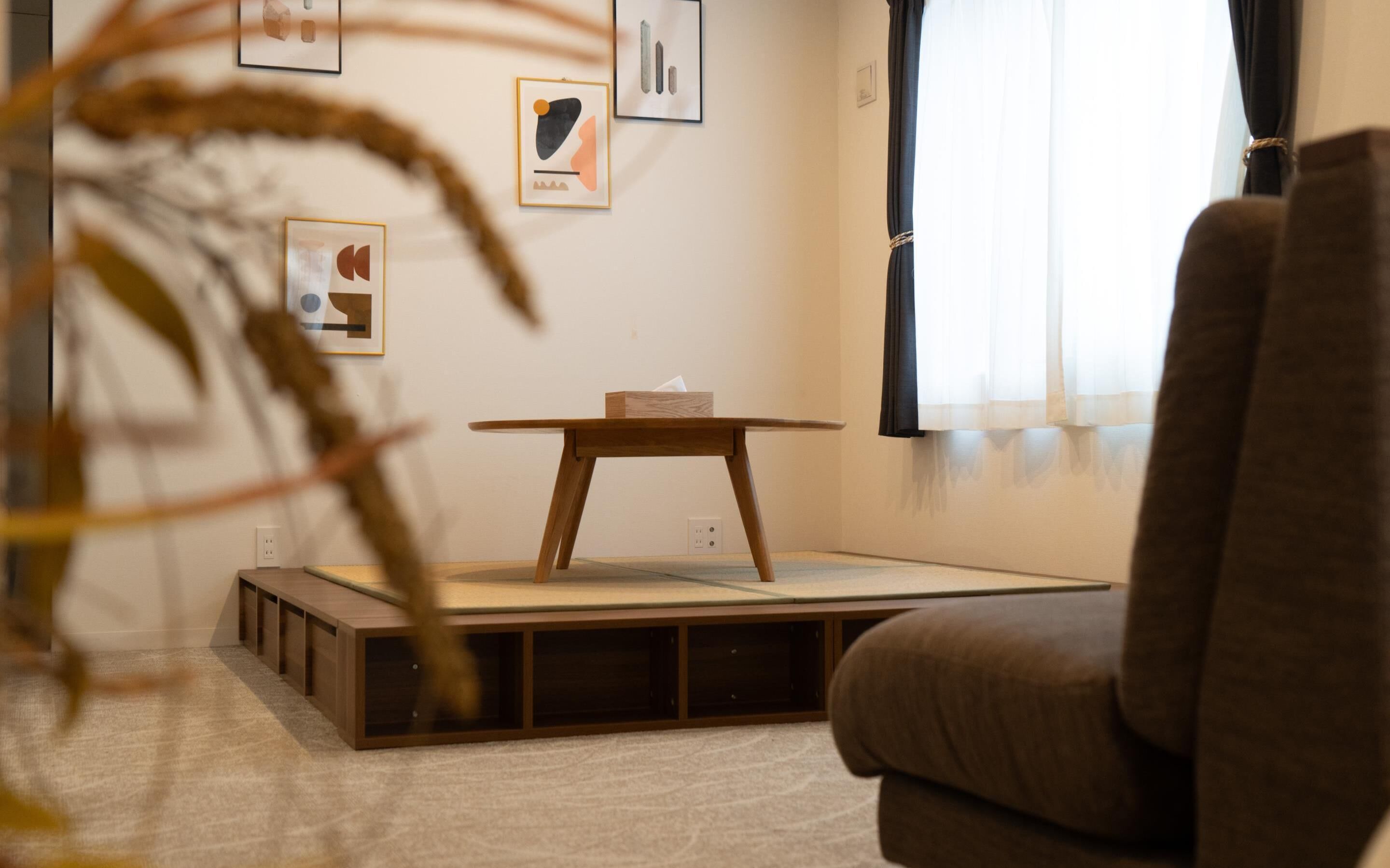 A minimalist living room with a low wooden table, a cushioned sofa, and a small wooden cabinet.
