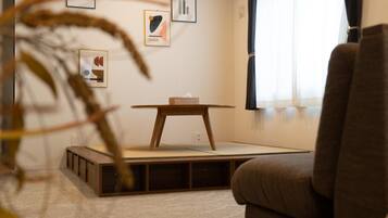 A minimalist living room with a low wooden table, a cushioned sofa, and a small wooden cabinet.