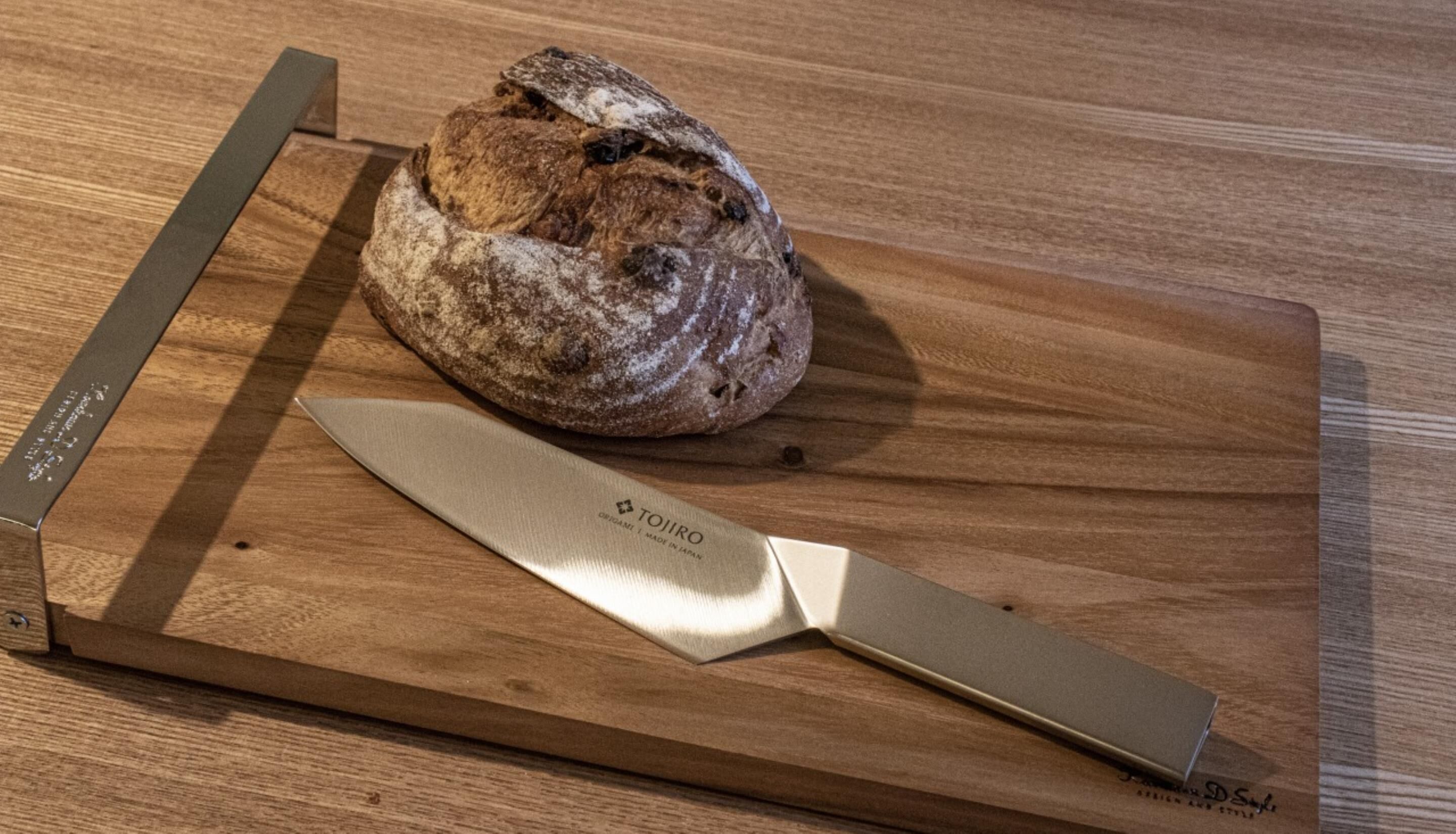 Una hogaza de pan sobre una tabla de madera con un cuchillo cerca.