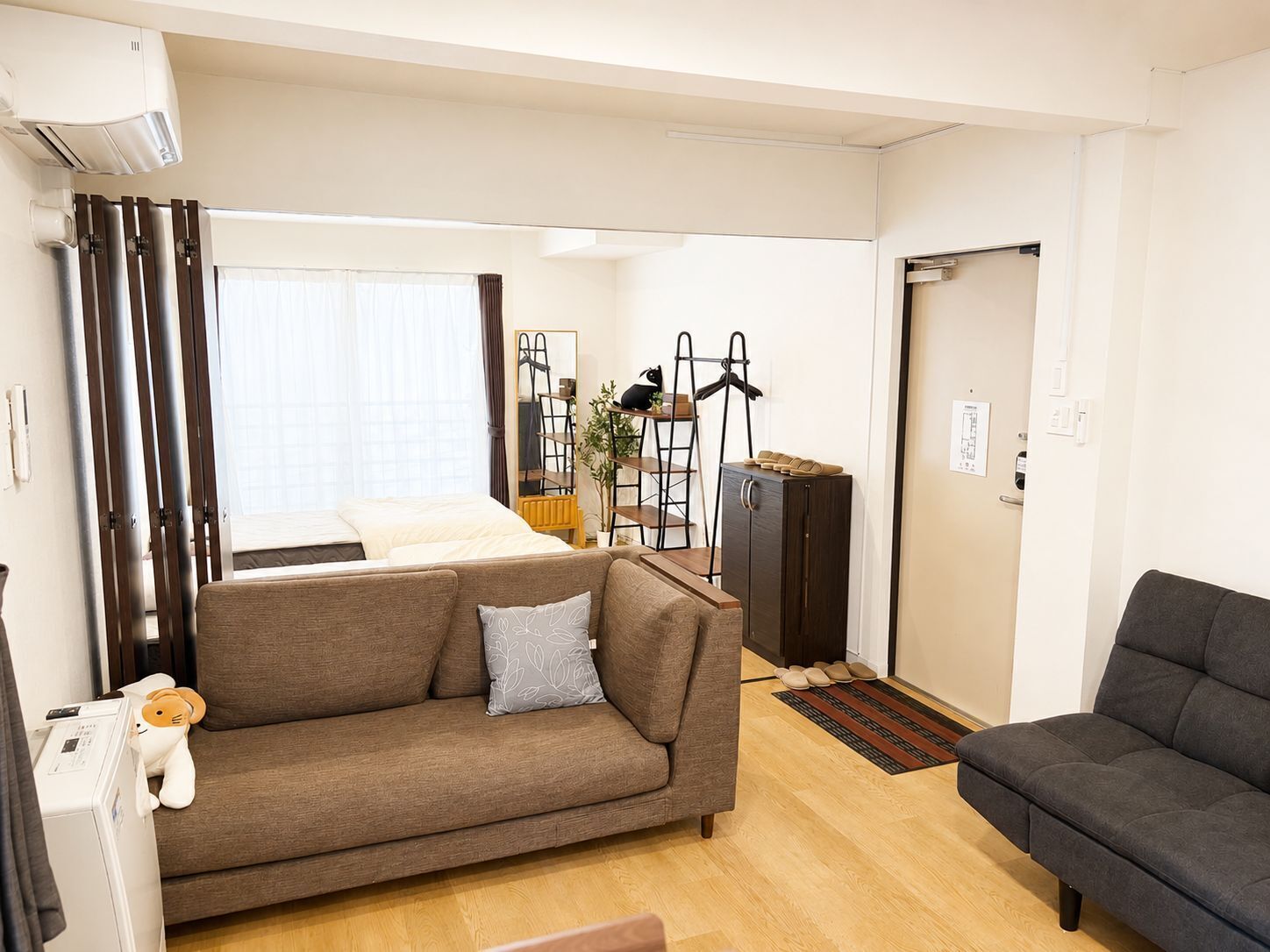 A modern living room with a sofa, a dark armchair, a small table, and a radiator.