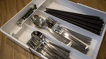 A white box containing various utensils including forks, spoons, and chopsticks.