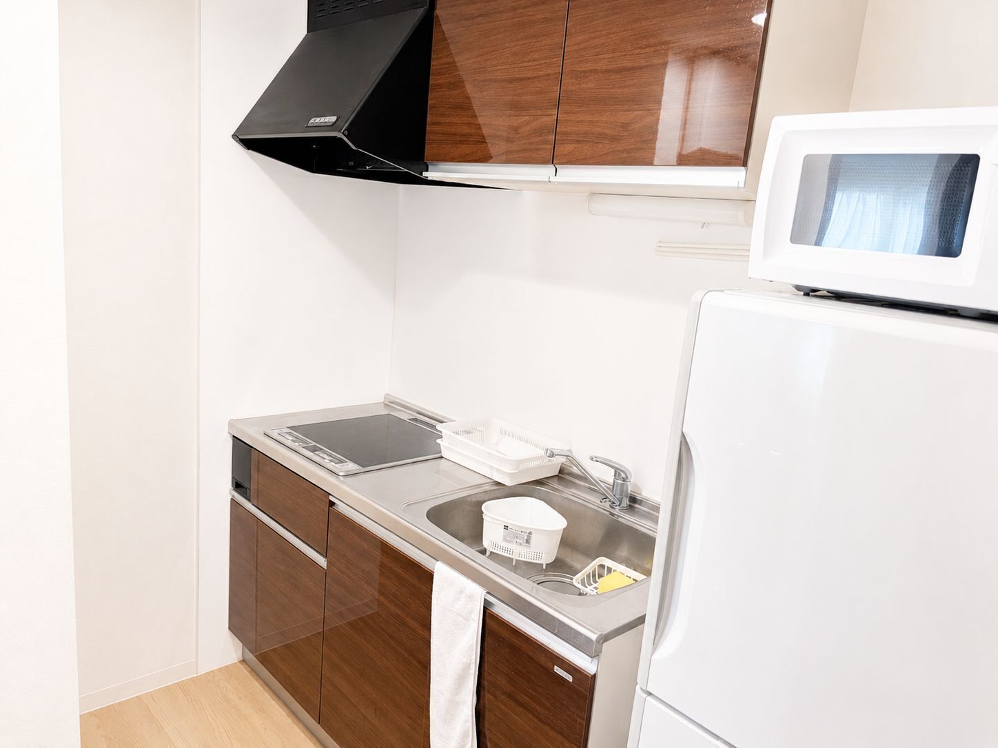 A compact kitchen with a microwave, sink, and a range hood.