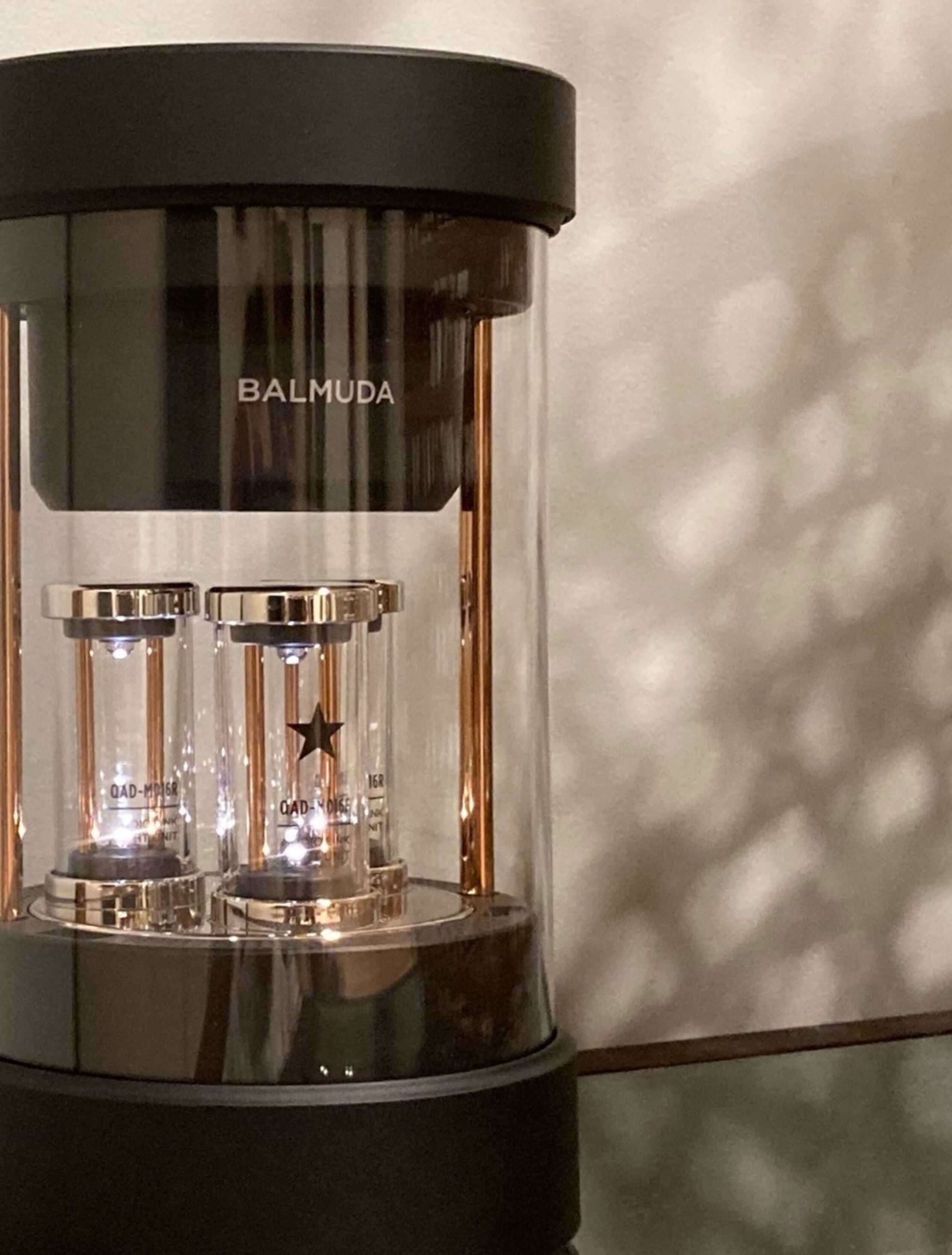 A black and clear coffee machine with the brand name BALMUDA visible on the top.