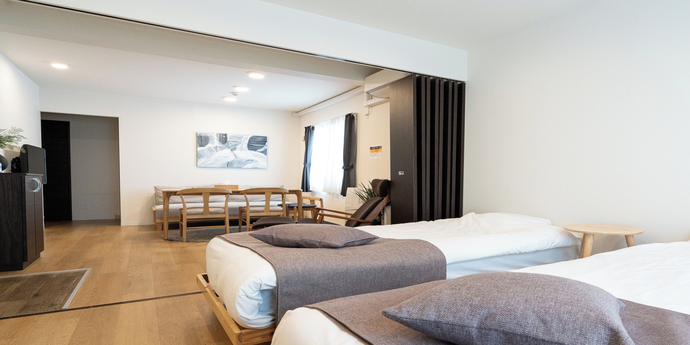 A modern hotel room with two beds, a desk, and a chair.