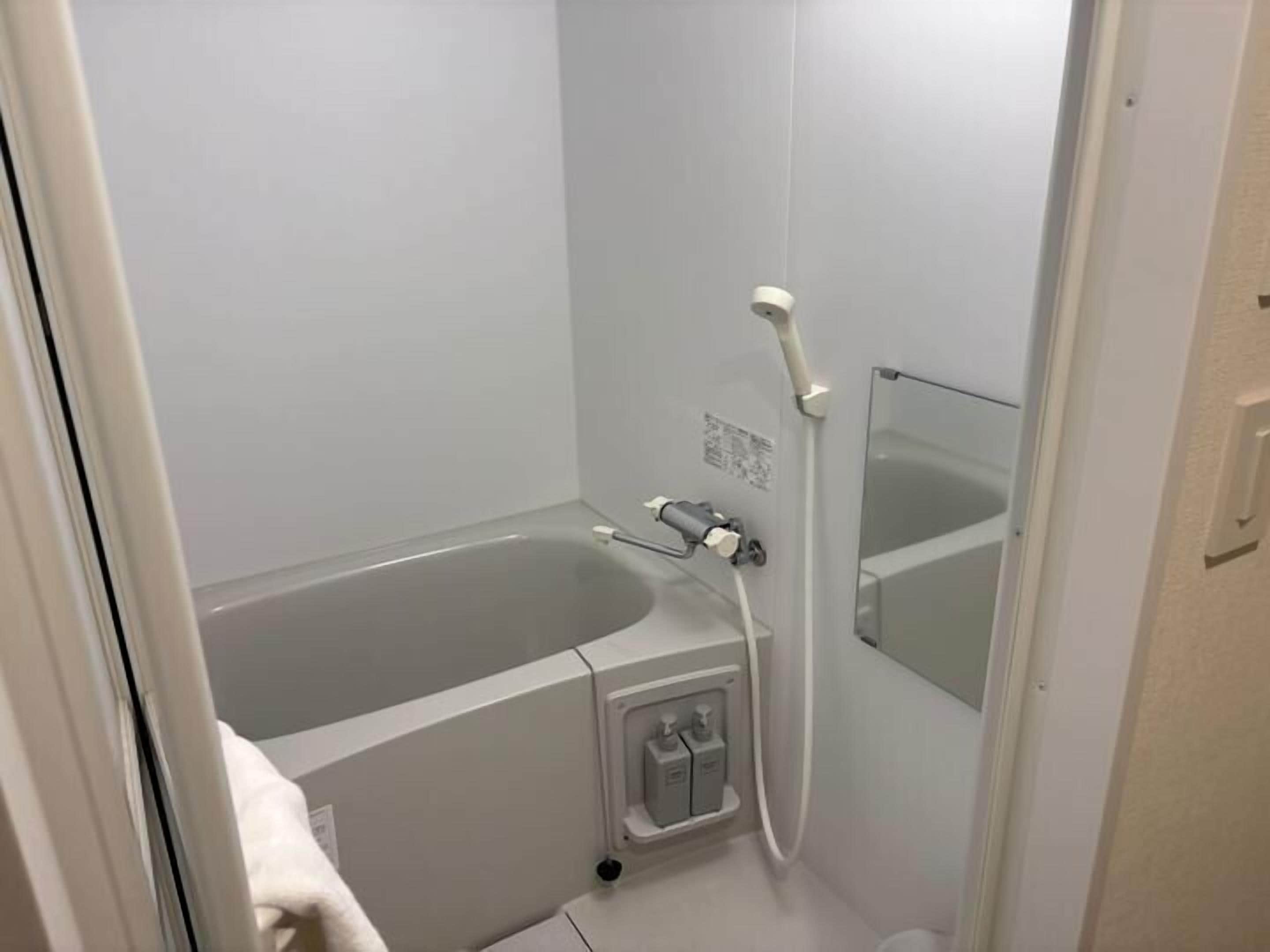 Ein kleines, modernes Badezimmer mit einer Badewanne, einer Dusche und einem Spiegel.
