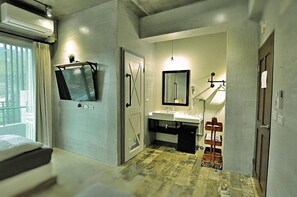 A hotel room with a bed, a large mirror, a sink, and a small cart. - Genuinn (Taitung)