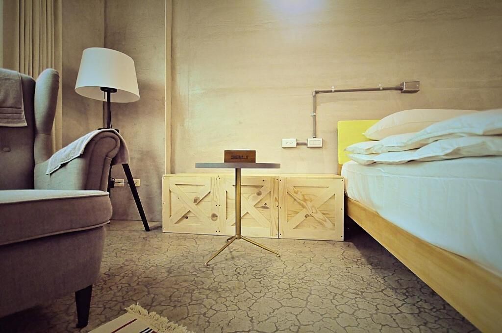 Una habitación de hotel con una cama, una silla, una mesita y una lámpara.