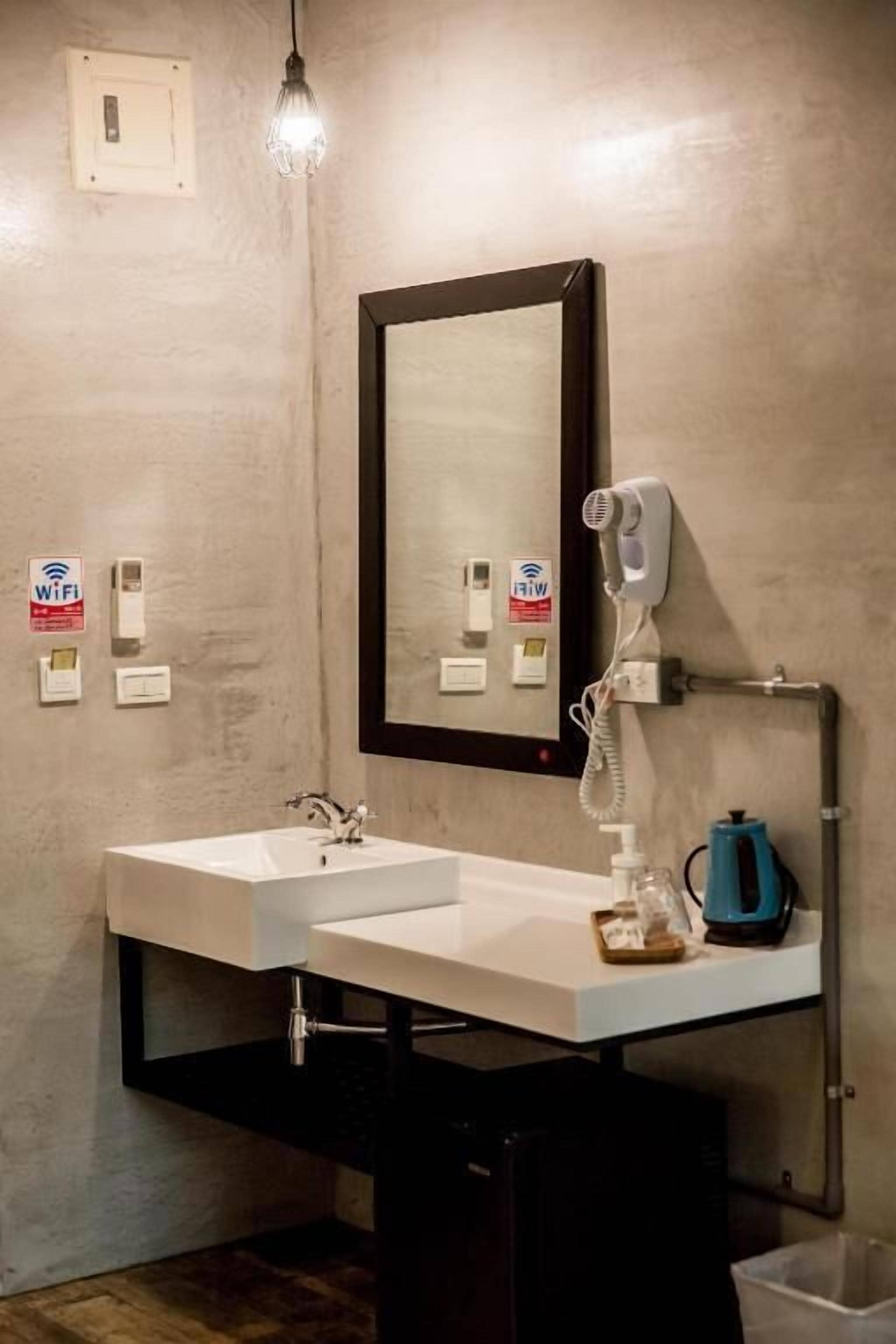 Un baño con lavamanos blanco, espejo, secador de pelo y toallero.