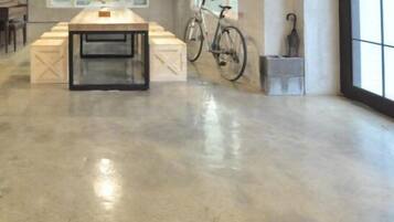 Una habitación amplia con una mesa grande, una bicicleta y una ventana con vistas.