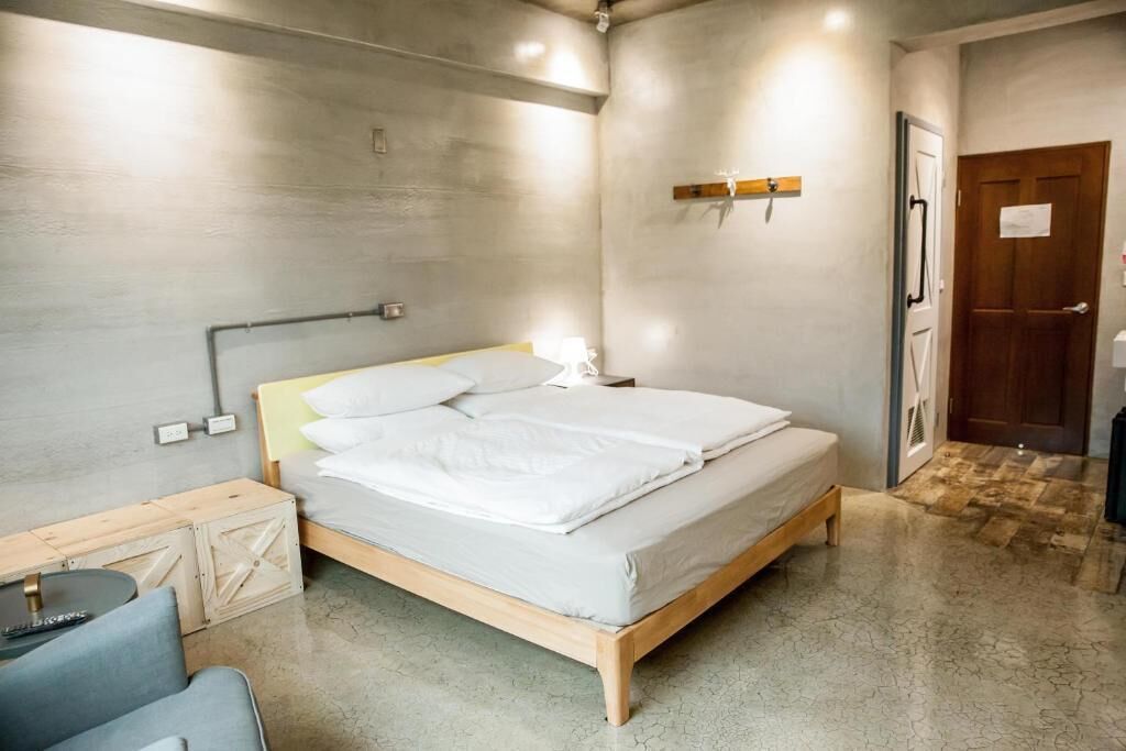 A bedroom with a bed, bedside table, lamp, and a door.