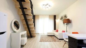 Un salon moderne avec un escalier, un canapé blanc, une table à manger et une lampe.