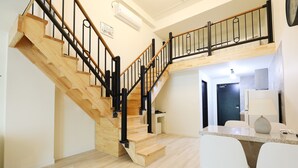 Un intérieur moderne avec un escalier en bois, un coin cuisine et un espace repas.