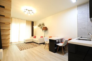 A modern living room with a sofa, a dining table, and a kitchen area with a sink.