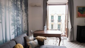 A living room with a gray sofa, a wooden coffee table, and a view of a building through a window with curtains.