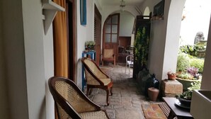 A covered porch with two wicker chairs, a small table, and potted plants. - Beatrice House (Galle)