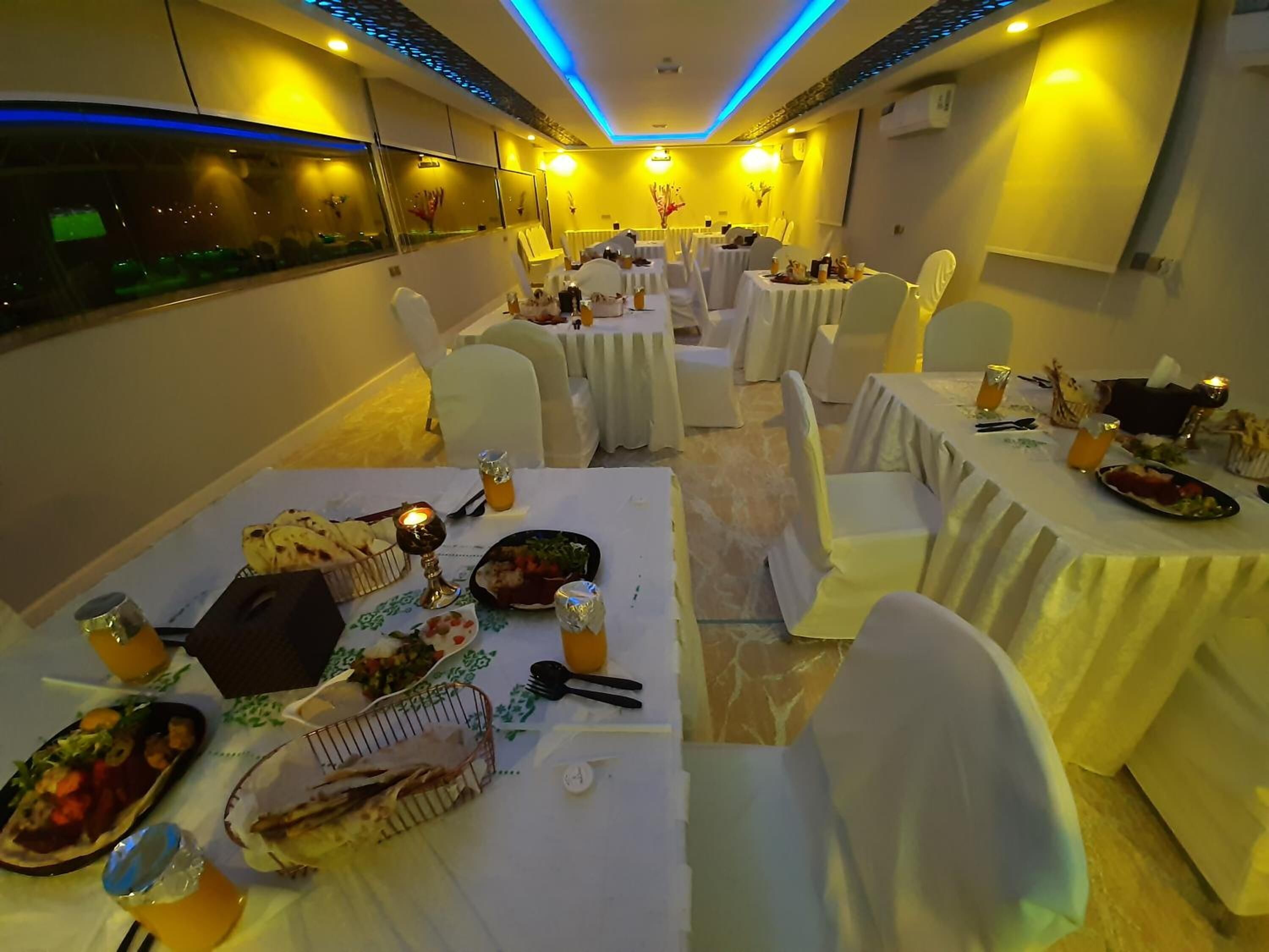 Een restaurant met meerdere tafels klaar voor diners, elk met witte tafelkleden en stoelen.