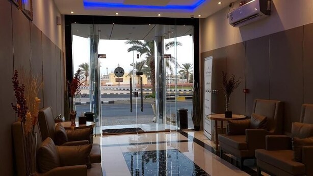 Een hotel lobby met zithoeken, een glazen ingang en uitzicht op buiten.