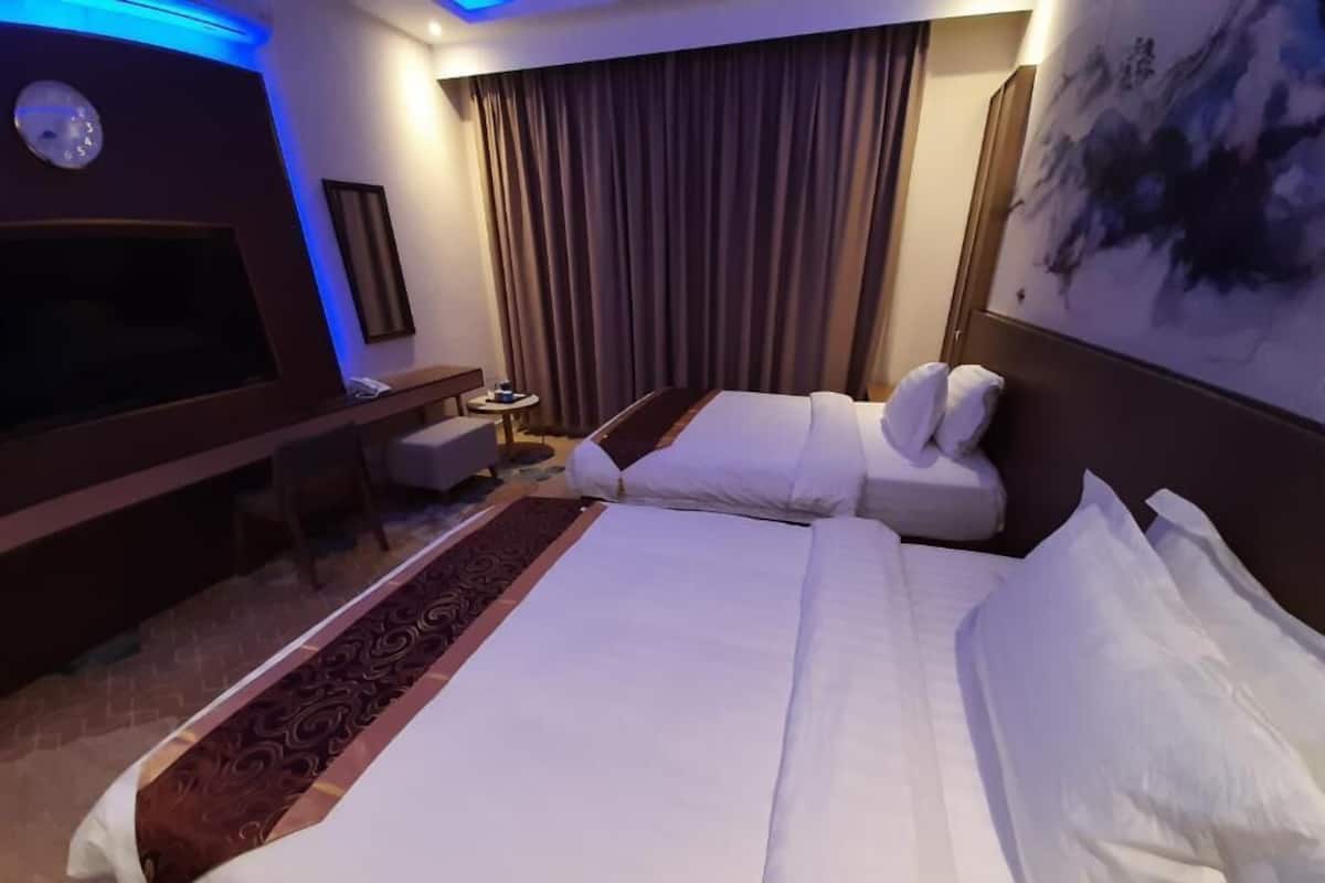 Een hotelkamer met een groot bed, een televisie, een bureau en een schilderij aan de muur.