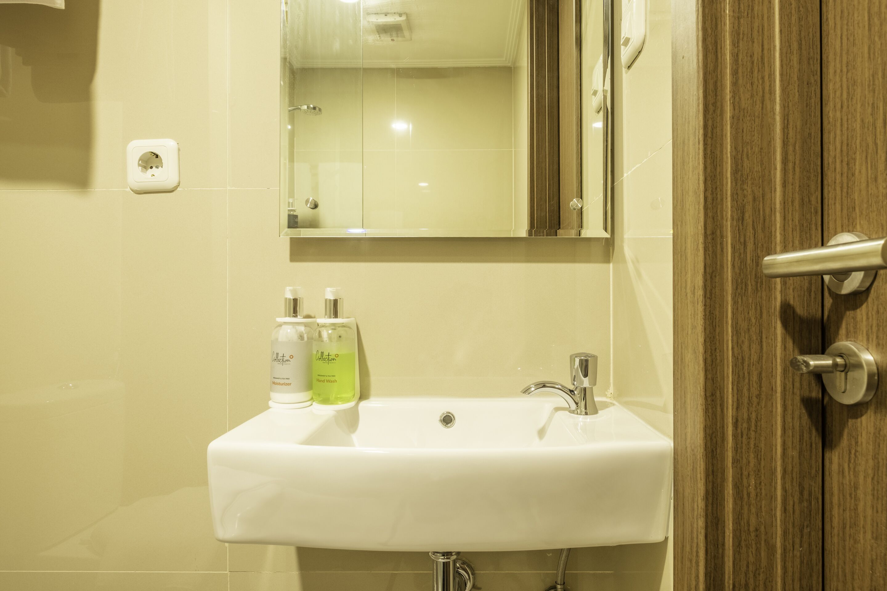 A bathroom with a white sink, a mirror, and two bottles of hand soap.