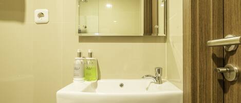 A bathroom with a white sink, a mirror, and two bottles of hand soap.