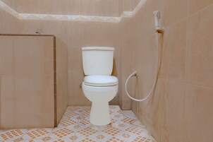 Un baño pequeño con azulejos, un inodoro, una cabina de ducha y un dispensador de papel higiénico.