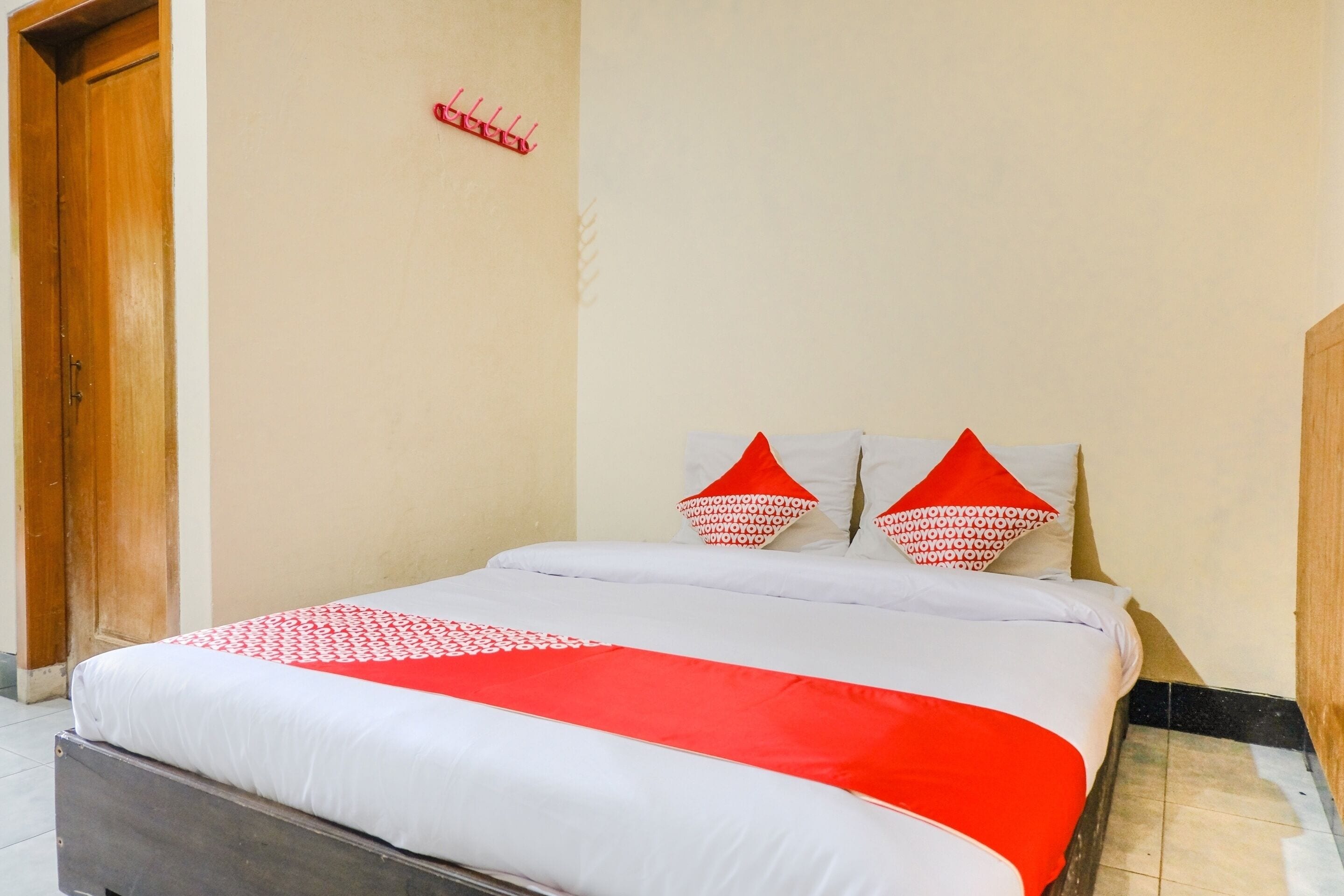 Une chambre d’hôtel avec un lit, une porte en bois et un crochet fixé au mur.