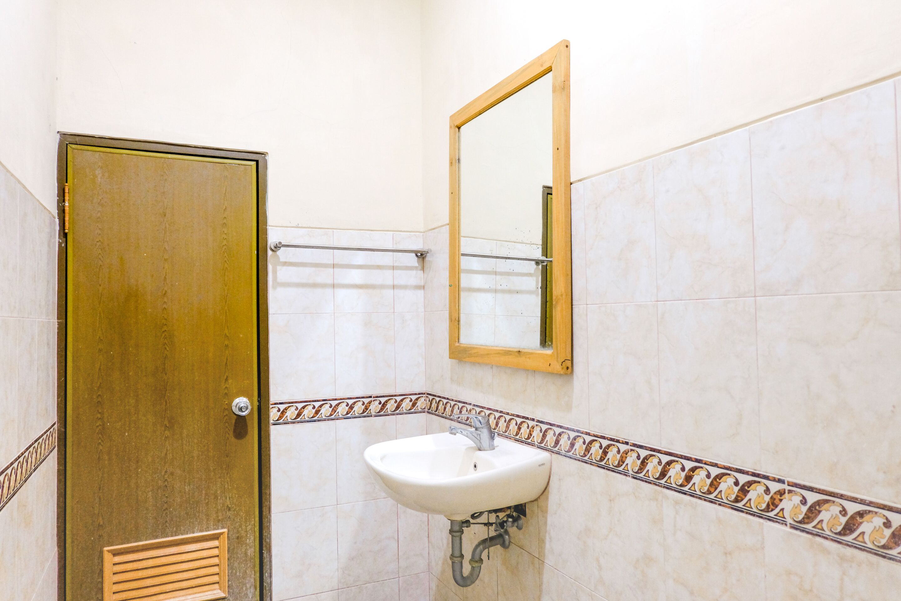 A bathroom with a white sink, a wooden door, and a mirror.