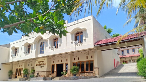 A hotel with a white facade, multiple windows, and a covered entrance area.