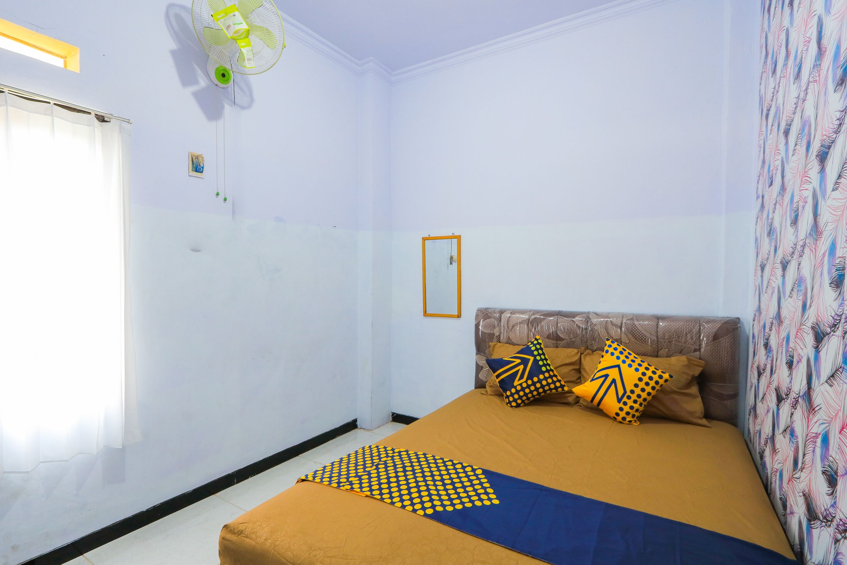 A bedroom with a bed, pillows, a fan, and a window.