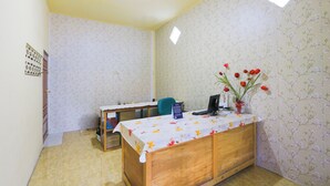 Een klein kantoor met een houten bureau, een stoel en een wand met bloemenprint.
