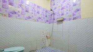 Een badkamer met toilet, douche en betegeling met een patroon.