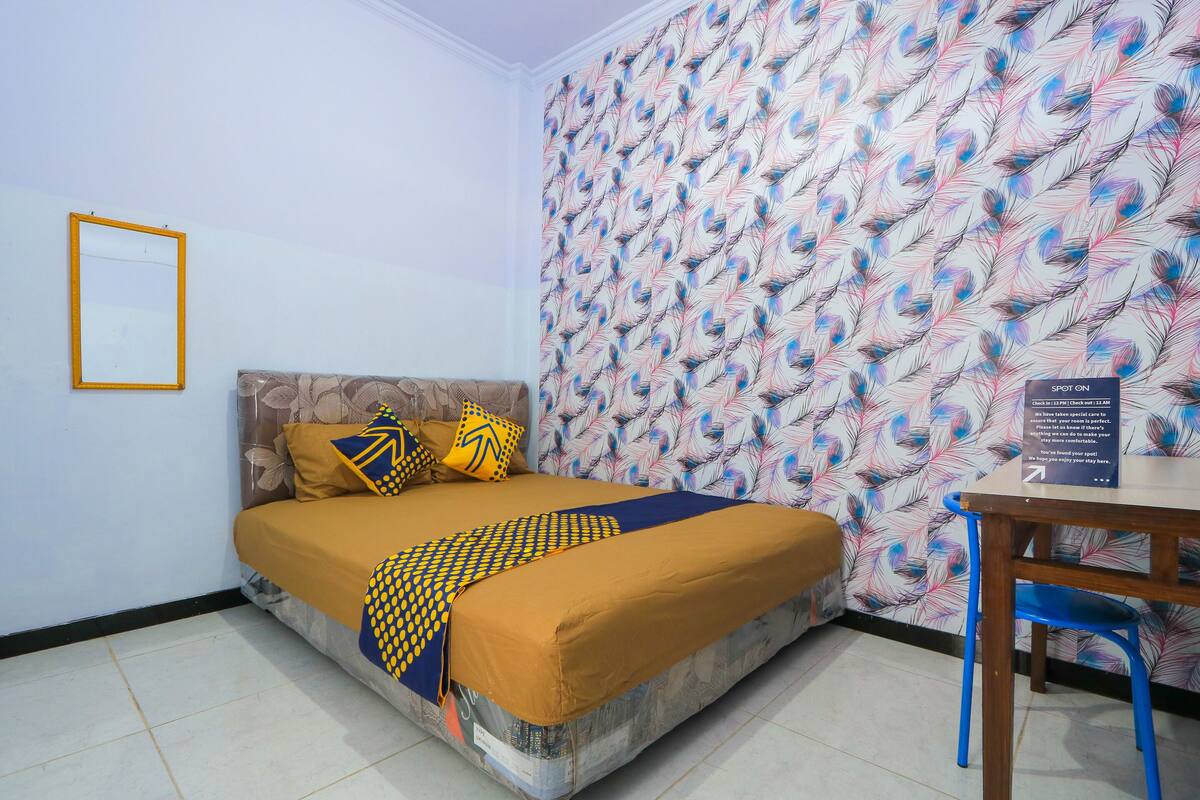A neatly arranged bedroom with a bed, pillows, a table, and a chair.