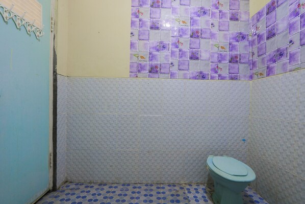 Un baño pequeño con inodoro, azulejos decorativos en las paredes y piso azul y blanco.