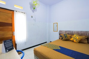A hotel room with a bed, a wooden door, a white curtain, a ceiling fan, and a sign indicating the room is occupied. - OYO 2497 Pesona Guest House (Banyuwangi)