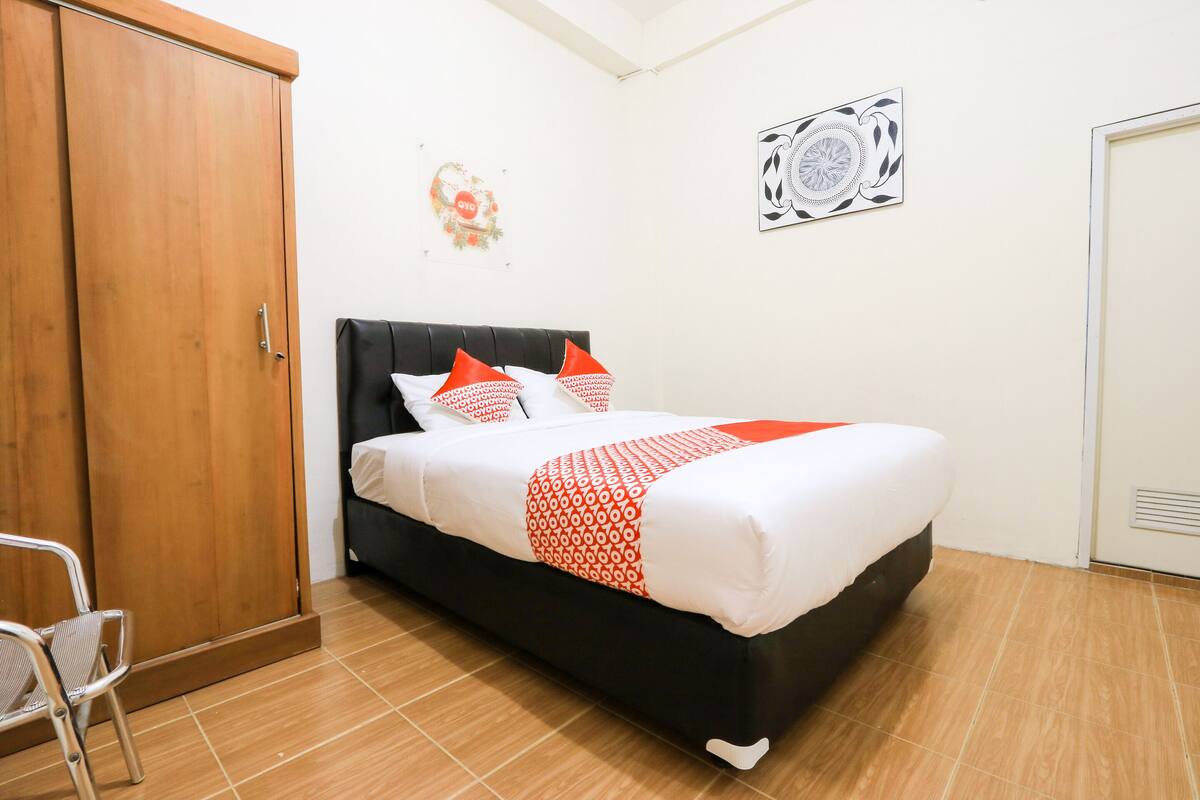 A bedroom with a bed, a wardrobe, and a chair.