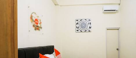 A hotel room with a bed, a door, an air conditioning unit, and a wall decoration.