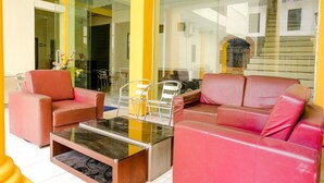 A modern living room with red leather sofas, a glass coffee table, and a dining area with chairs and a table. - OYO 2614 Demasto Homestay (Jember)